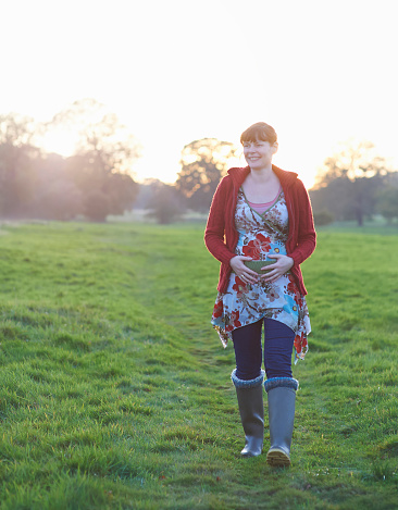 Pregnant woman walking in countryside.